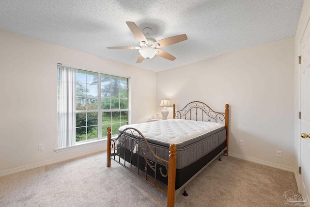 carpeted bedroom with ceiling fan and a textured ceiling