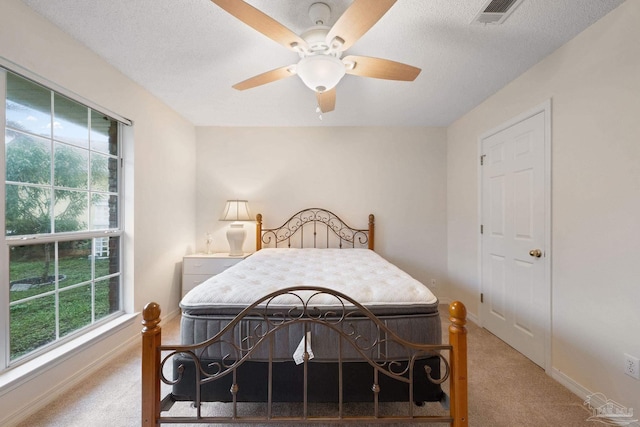 bedroom with carpet flooring, multiple windows, ceiling fan, and a textured ceiling