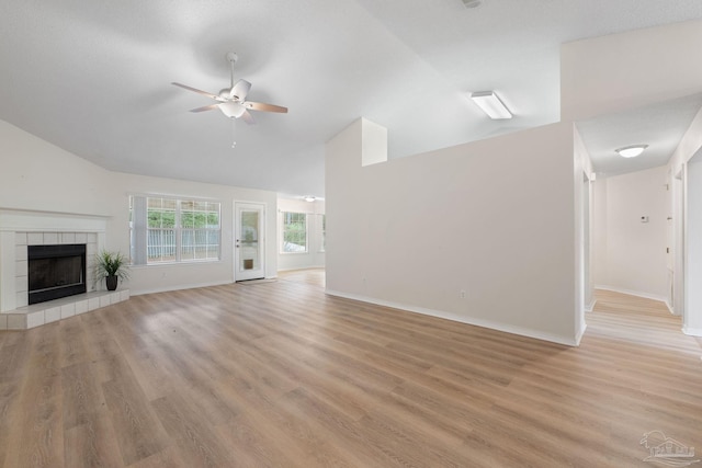 unfurnished living room with a tile fireplace, ceiling fan, light hardwood / wood-style floors, and lofted ceiling