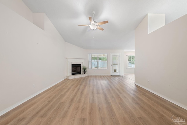 unfurnished living room featuring a tile fireplace, light hardwood / wood-style floors, and ceiling fan