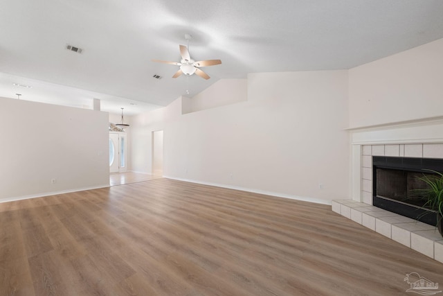 unfurnished living room featuring hardwood / wood-style flooring, ceiling fan, high vaulted ceiling, and a tile fireplace