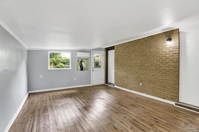 6790 Data St, Pensacola, FL 32504 - unfurnished room with a wall mounted AC, brick wall, wood finished floors, and ornamental molding