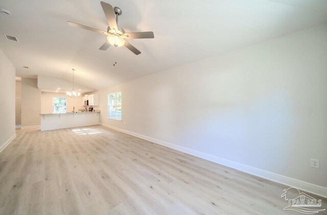 unfurnished living room featuring ceiling fan with notable chandelier, light wood-type flooring, and lofted ceiling