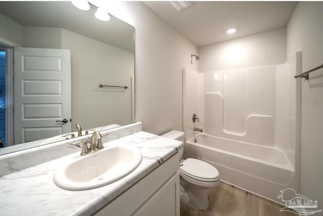 full bathroom featuring hardwood / wood-style flooring, vanity, toilet, and tub / shower combination