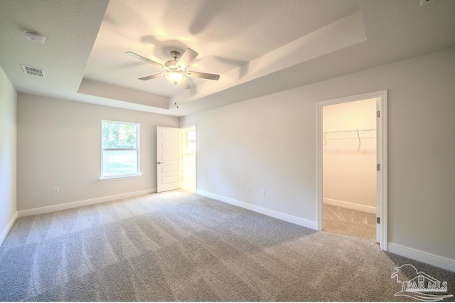 carpeted empty room featuring a raised ceiling and ceiling fan