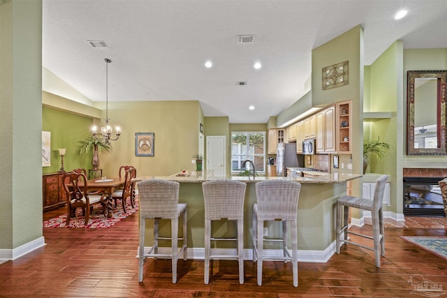 kitchen with a breakfast bar area, light stone counters, visible vents, and stainless steel appliances