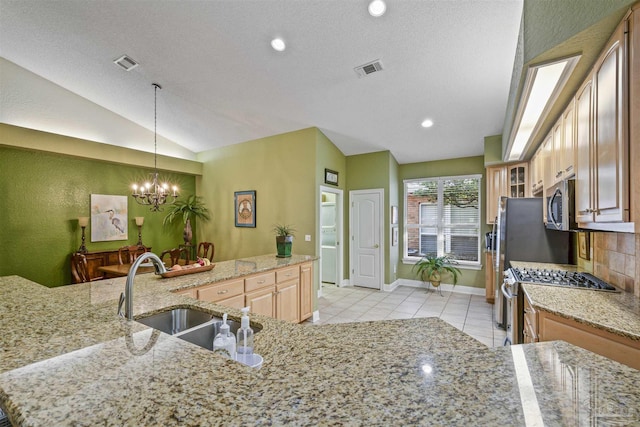 kitchen with visible vents, vaulted ceiling, a notable chandelier, stainless steel appliances, and a sink