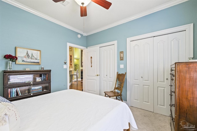 bedroom with visible vents, ceiling fan, ornamental molding, light colored carpet, and two closets