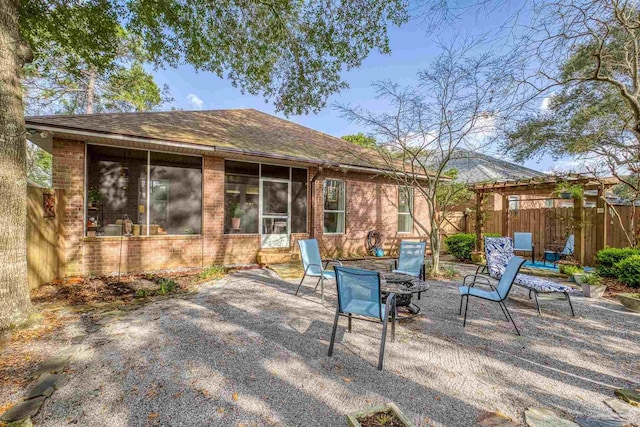 view of patio / terrace featuring fence, a sunroom, and a fire pit