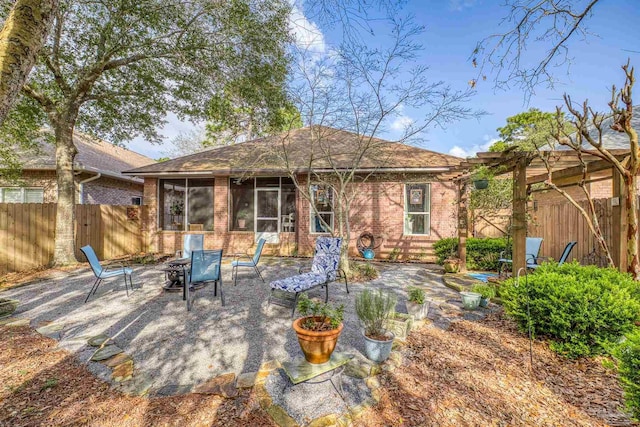 rear view of house featuring brick siding, a patio, a fire pit, and fence