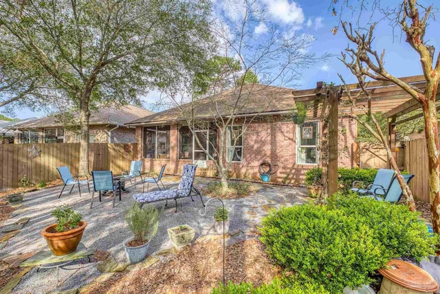 rear view of house with a patio, a fenced backyard, a pergola, a sunroom, and brick siding