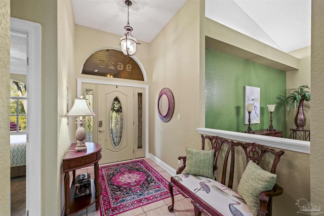 foyer with lofted ceiling, a textured wall, baseboards, and tile patterned floors