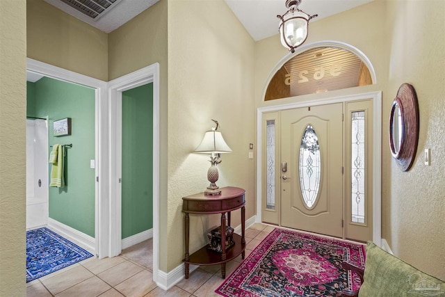 tiled foyer entrance with visible vents, baseboards, and a chandelier