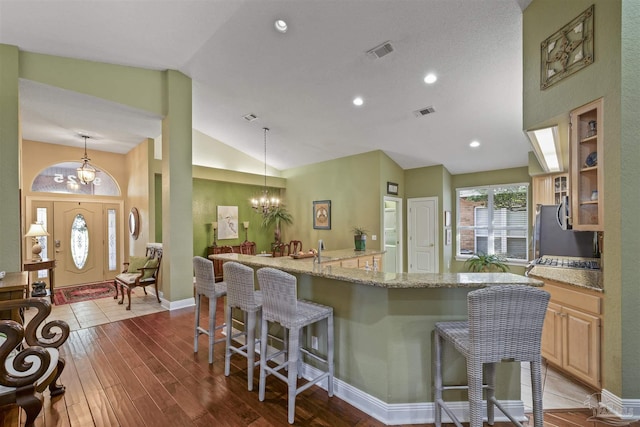 kitchen featuring a chandelier, visible vents, a large island with sink, and a kitchen breakfast bar