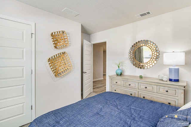 bedroom with a textured ceiling and hardwood / wood-style flooring