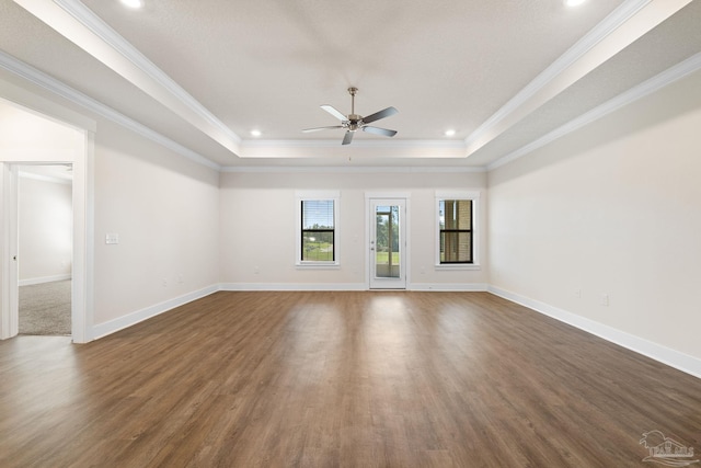 empty room with dark wood-type flooring, crown molding, a tray ceiling, and ceiling fan