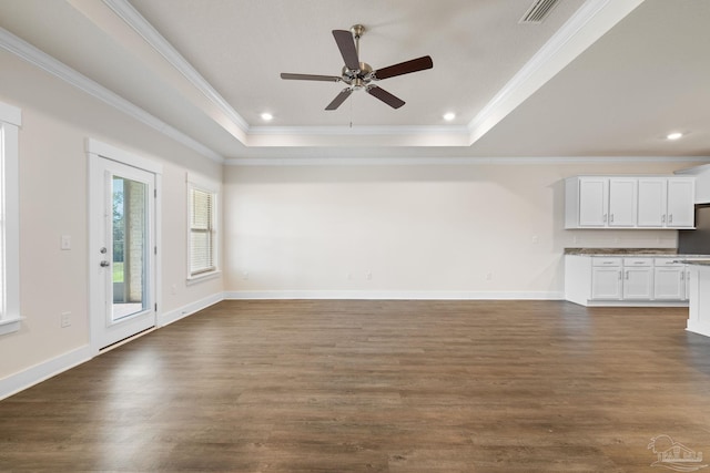 unfurnished living room with crown molding, a raised ceiling, ceiling fan, and dark hardwood / wood-style flooring