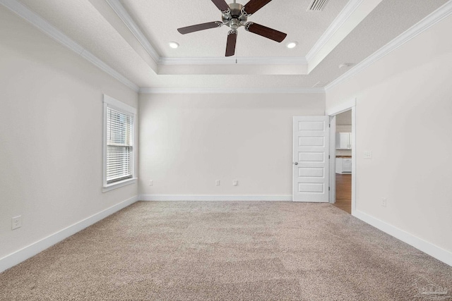 empty room with crown molding, a textured ceiling, a tray ceiling, and carpet floors