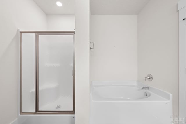 bathroom featuring a textured ceiling and shower with separate bathtub