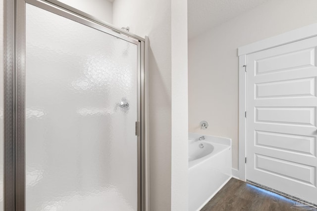 bathroom featuring plus walk in shower and wood-type flooring