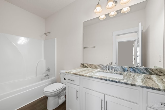 full bathroom with bathtub / shower combination, vanity, hardwood / wood-style floors, and toilet