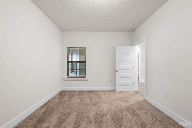 carpeted spare room with a textured ceiling