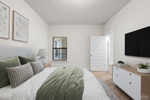 bedroom featuring a textured ceiling and light colored carpet