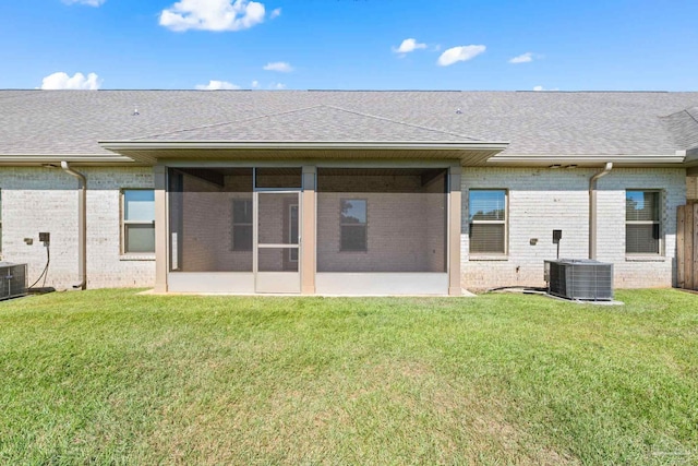 back of property with central air condition unit, a sunroom, a patio, and a lawn