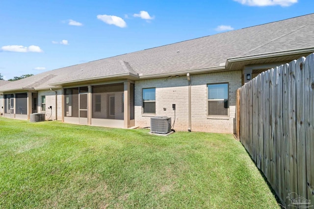 rear view of house with a yard, cooling unit, and a sunroom