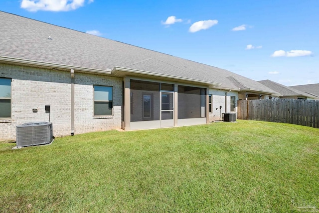 rear view of property featuring central AC, a lawn, and a sunroom