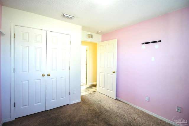 unfurnished bedroom featuring a closet, a textured ceiling, and dark colored carpet