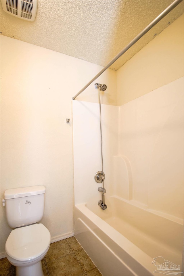 bathroom with a textured ceiling, tile patterned flooring, shower / bathtub combination, and toilet