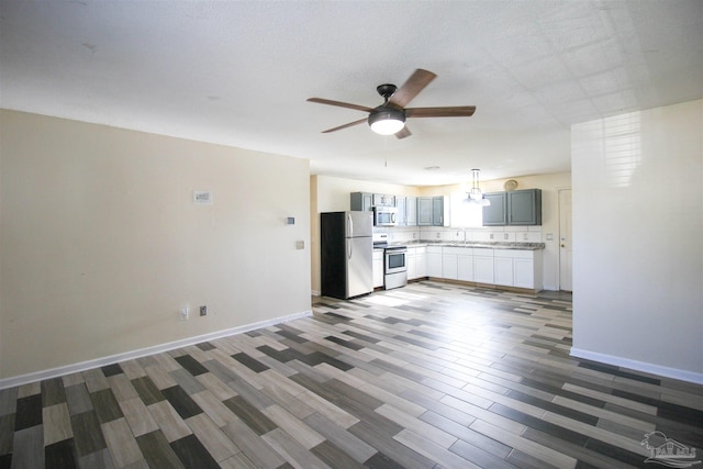 unfurnished living room featuring dark hardwood / wood-style floors, ceiling fan, and sink