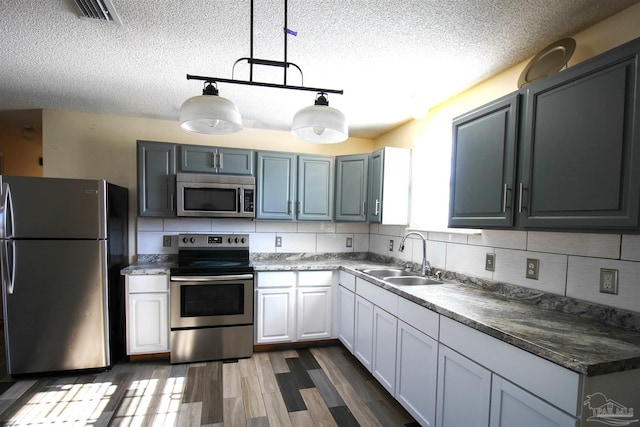 kitchen with sink, hanging light fixtures, decorative backsplash, dark hardwood / wood-style flooring, and stainless steel appliances