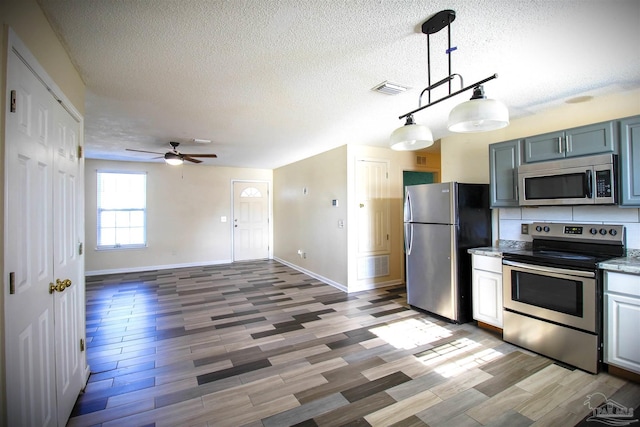 kitchen featuring a textured ceiling, wood-type flooring, stainless steel appliances, and hanging light fixtures