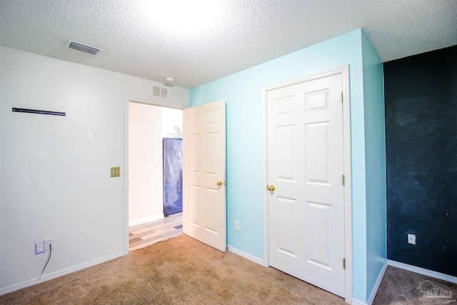 unfurnished bedroom featuring light colored carpet, a textured ceiling, and a closet