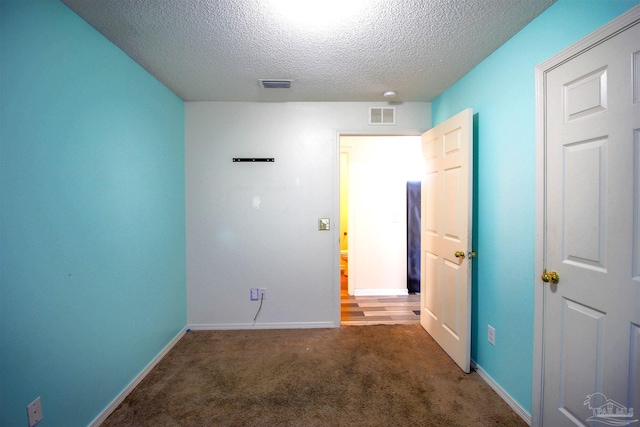 spare room with dark colored carpet and a textured ceiling