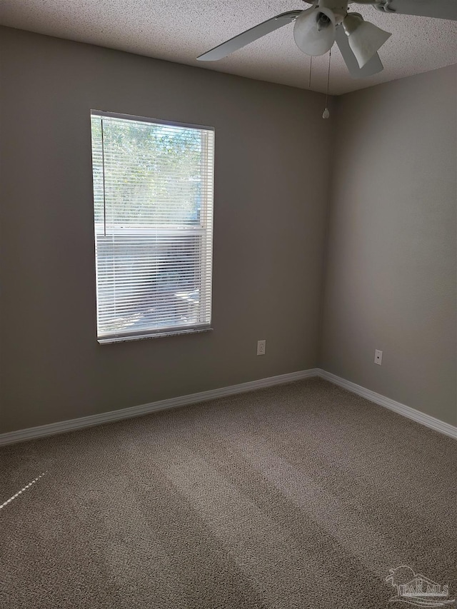 carpeted spare room with a ceiling fan, baseboards, and a textured ceiling