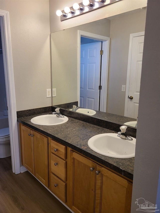 bathroom featuring double vanity, toilet, and a sink