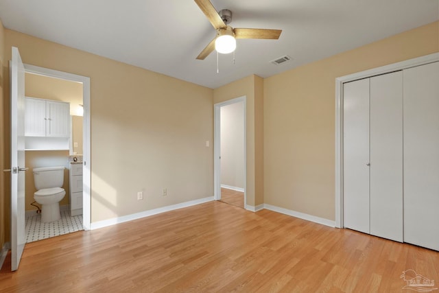 unfurnished bedroom featuring ceiling fan, light hardwood / wood-style floors, a closet, and ensuite bath