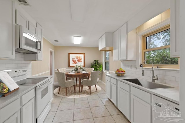 kitchen featuring decorative backsplash, white appliances, sink, white cabinets, and light tile patterned flooring