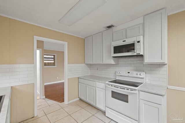 kitchen with white cabinetry, white appliances, ornamental molding, and light tile patterned floors