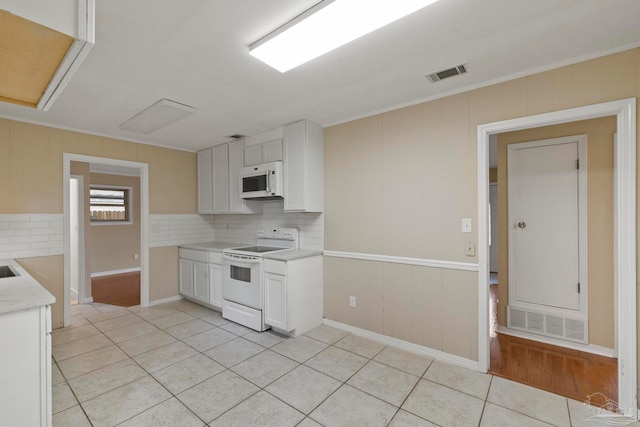 kitchen with tasteful backsplash, light tile patterned flooring, white appliances, white cabinets, and ornamental molding