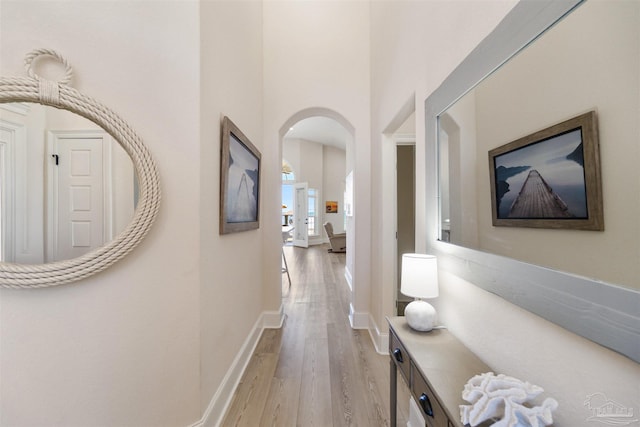 5136 Point Shores Ln, Gulf Breeze, FL 32563 - corridor featuring baseboards, arched walkways, and light wood finished floors