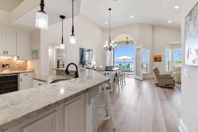 5136 Point Shores Ln, Gulf Breeze, FL 32563 - kitchen featuring a sink, high vaulted ceiling, a notable chandelier, light wood-style floors, and white cabinetry