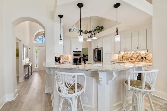 5136 Point Shores Ln, Gulf Breeze, FL 32563 - kitchen featuring light wood-type flooring, white cabinetry, a towering ceiling, and stainless steel appliances