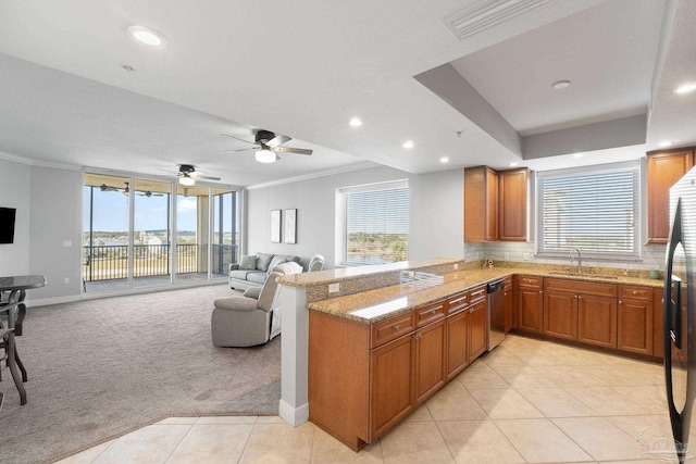 kitchen with brown cabinets, light colored carpet, stainless steel dishwasher, open floor plan, and a peninsula