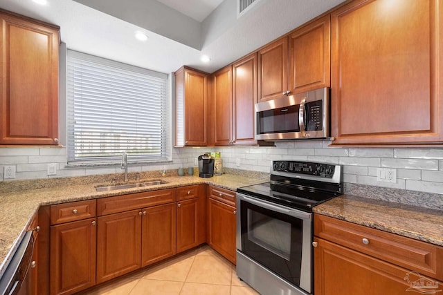 kitchen with light stone counters, brown cabinets, tasteful backsplash, appliances with stainless steel finishes, and a sink