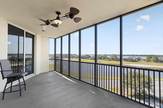 unfurnished sunroom featuring a water view and a ceiling fan