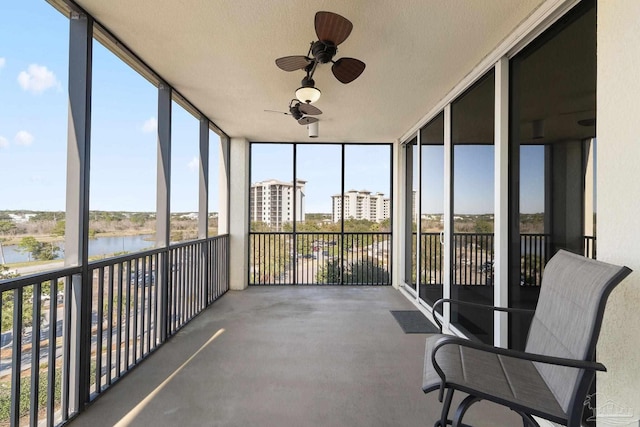 unfurnished sunroom featuring a water view and a ceiling fan